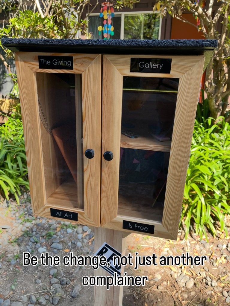 The Giving Gallery cabinet closed, showing its new signs and free-art message.