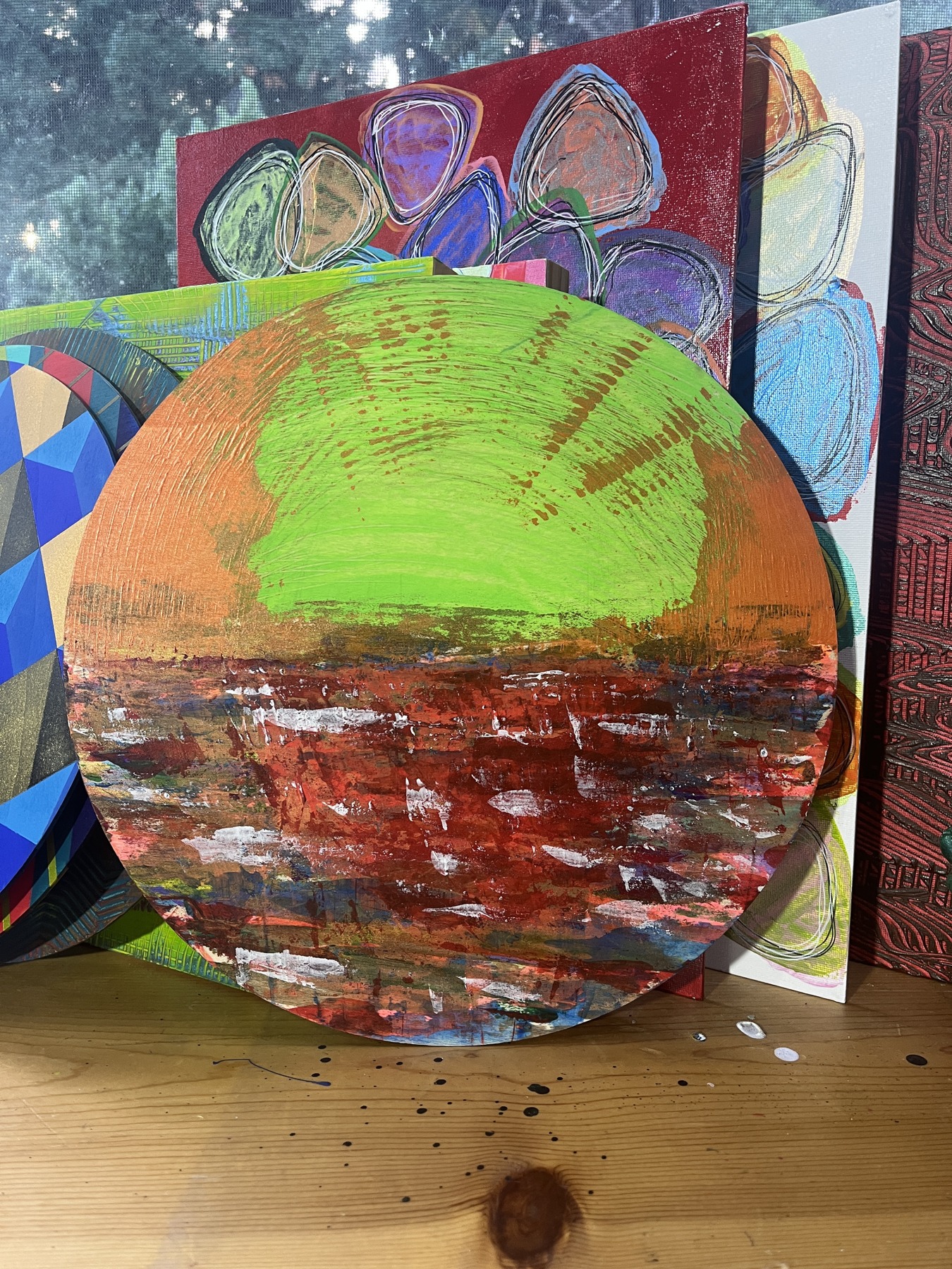 Art Drop #11 (estimated match): Magic Hour: Reflective, #MM126: circular panel with a green and orange sky above a red and white textured foreground